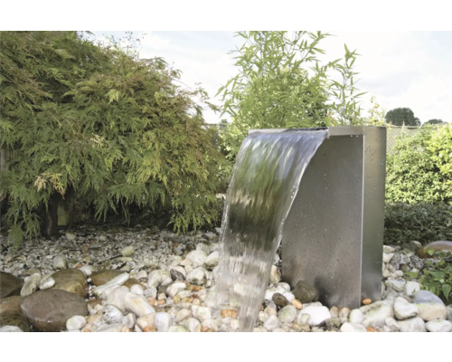 Tuinscene met een roestvrijstalen waterval tussen stenen en planten