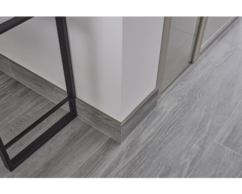 Gedetailleerde opname van laminaatvloer met grijze houtlook en plinten