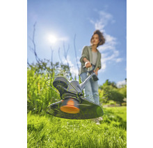 Vrouw werkt met een grastrimmer in de tuin.