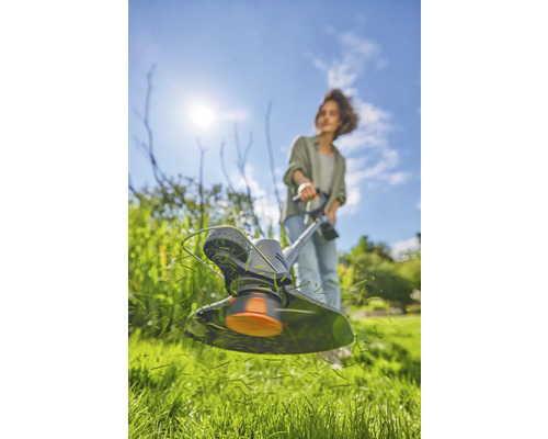 Vrouw werkt met een grastrimmer in de tuin.
