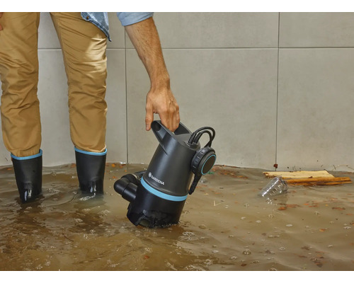 Man met Gardena vuilwaterpomp in overstroomde ruimte.