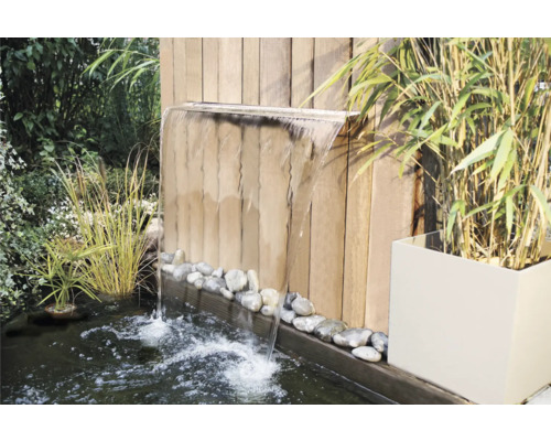 Vijver in de tuin met waterval tegen houten wand met beplanting
