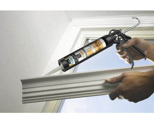 Iemand brengt met een kitpistool lijm aan op een sierlijst