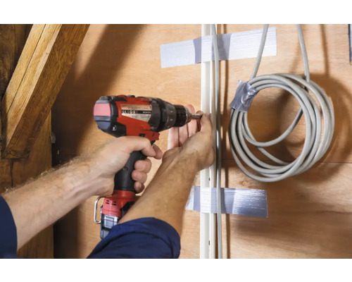 Ambachtsman bevestigt kabelkanaal aan houten wand met accuboormachine
