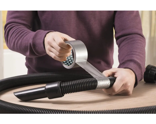 Een persoon repareert een stofzuigerslang met ducttape.