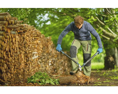 Man hakt hout met een takkenschaar naast een stapel hout.