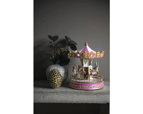Decoratieve carrousel met verlichting, vaas en dennenappel op een tafel
