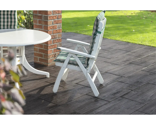 Tuinscene met witte tuintafel, tuinstoel met kussen en vloerplaten