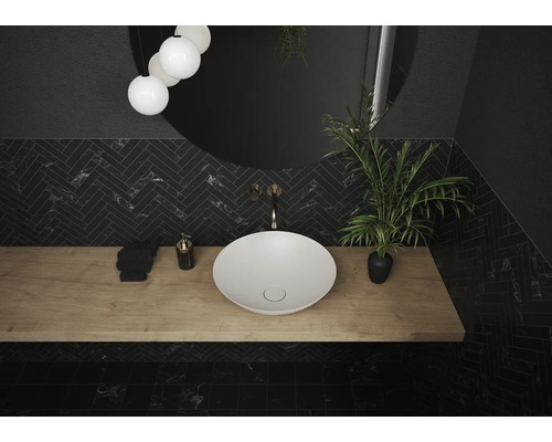 Badkamer met opzetwastafel, spiegel, kraan en plant op een houten plank.