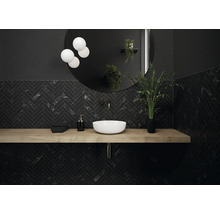 Moderne badkamer met zwart visgraatmotief, ronde spiegel, wastafel en houten werkblad
