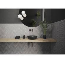 Badkamer met wastafel, ronde spiegel en grijze visgraattegels.