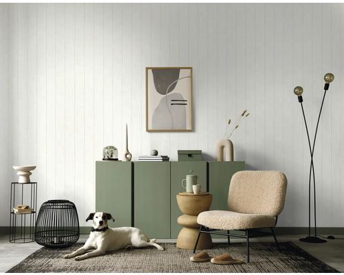 Woonkamer met groene commode, decoraties, fauteuil en hond op een tapijt