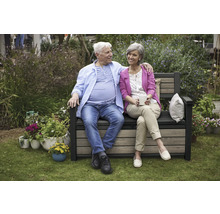 Een echtpaar zit op een tuinbank met opbergruimte en geniet van de tijd in de tuin.