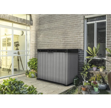 Kunststof tuingereedschapskast op een terras voor een bakstenen muur.