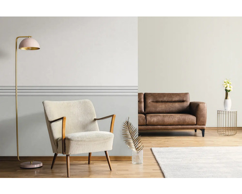 Woonkamer met fauteuil, bank, staande lamp en decoratie op een houten vloer