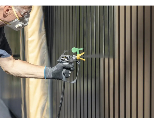 Persoon lakt hek met verfspuit