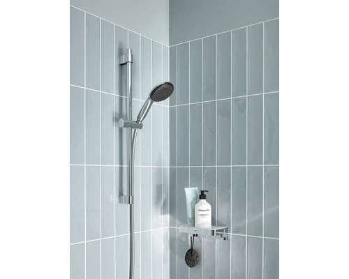 Douchecabine met douchekop aan stang, plank met verzorgingsproducten en grijze tegels