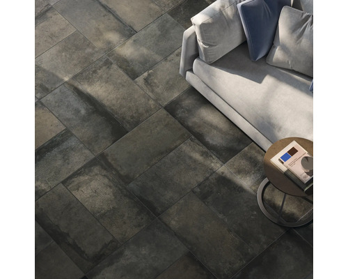 Vloer met donkere tegels in steenlook, gelegd in visgraatmotief, bank en bijzettafel