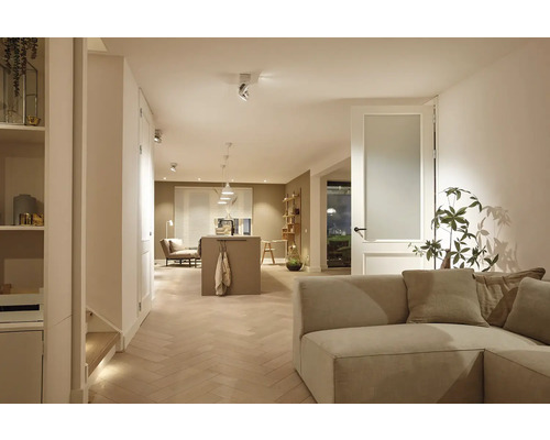 Lichte woonkamer met bank, houten vloer en open keuken