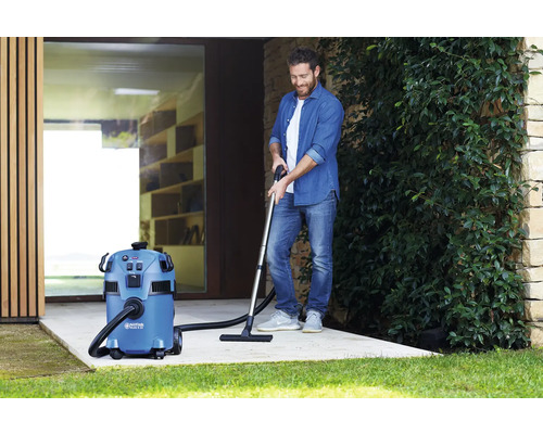 Een man gebruikt een alleszuiger buiten voor reiniging.