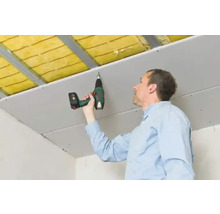 Een persoon bevestigt een gipsplaat aan een plafond met een accuschroevendraaier.