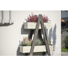 Houten ladderrek met beplante bloembakken tegen een huismuur