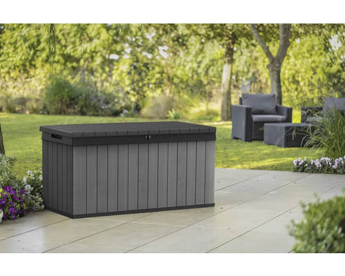 Grijze kunststof tuinkist op een terras met tuinmeubilair op de achtergrond