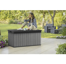 Tuinscene met grijze kunststof opbergbox met vrouw erop