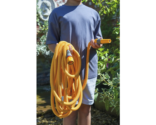 Een persoon houdt een flexibele tuinslang vast met sproeikop en aansluitstuk.