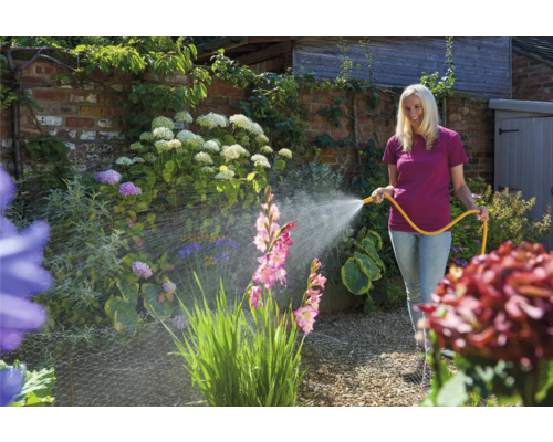 Vrouw besproeit tuin met tuinslang