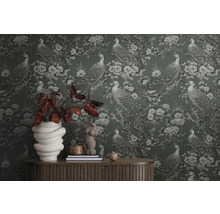 Detailopname van een muur met behang met pauwen en bloemenmotief, met een tafel en decoraties ervoor