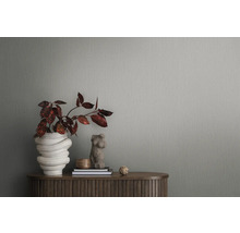 Detailopname van een grijs structuurbehang met plant en decoraties op een houten tafel