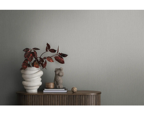 Detailopname van een grijs structuurbehang met plant en decoraties op een houten tafel