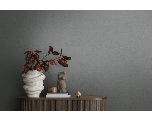 Close-up van een grijs vliesbehang met structuur op de achtergrond van een kamer met een dressoir en decoratie