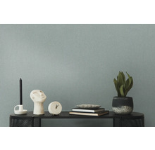 Decoratieve opstelling met kaars, beeld, klok, boeken en kamerplant op een plank