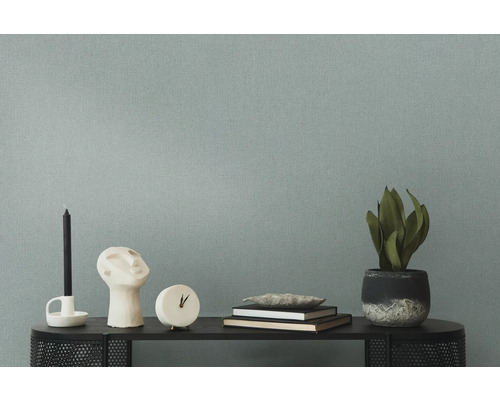 Decoratieve opstelling met kaars, beeld, klok, boeken en kamerplant op een plank