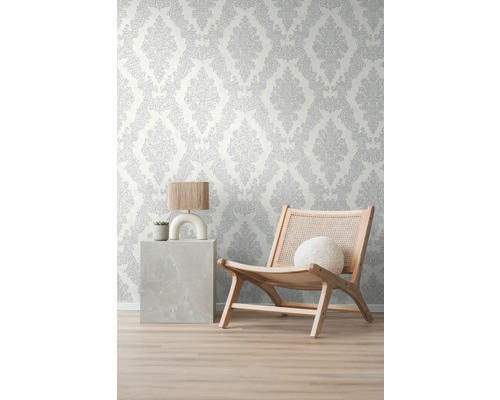 Kamerweergave met patroonbehang, een fauteuil en een bijzettafel met lamp en plant