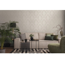 Woonkamer met patroonbehang, bank, kamerplant en decoratieve elementen voor een gezellige sfeer