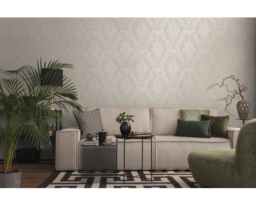 Woonkamer met patroonbehang, bank, kamerplant en decoratieve elementen voor een gezellige sfeer