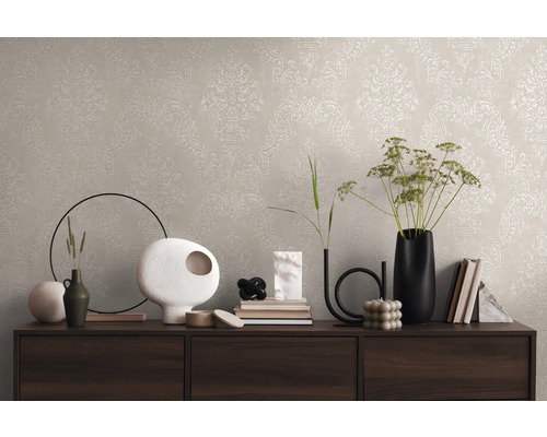 Wanddecoratie met beige behang en klassiek patroon op een dressoir met decoratieve vazen en boeken