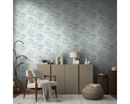 Woonkamer met behang met wolkenpatroon, fauteuil, dressoir en decoratieve elementen voor een huiselijke sfeer