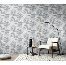 Een kamer met behang met wolkenpatroon, een fauteuil, een vloerlamp en een bijzettafel.