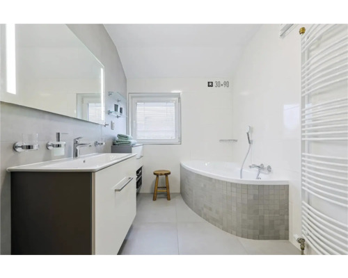Badkamer met wastafel, spiegel, bad en radiator
