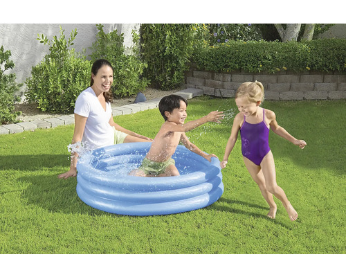 Opblaasbaar kinderzwembad met spelende kinderen en een vrouw in de tuin.