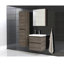 Badkamer met wastafel, spiegelkast en hoge kast in houtlook tegen een donkere tegelachtergrond