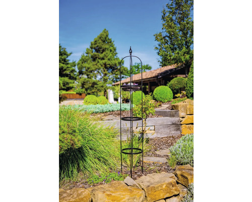 Metalen plantensteun met drie plateaus in de tuin.