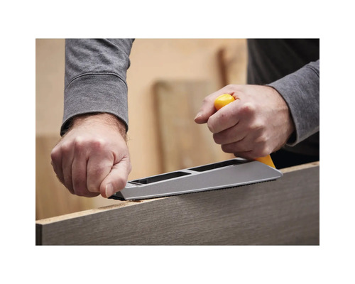 Een persoon gebruikt een schaaf om een stuk hout te bewerken.