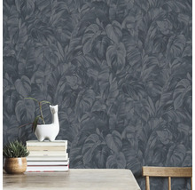 Wand met donker behang met bladeren, versierd met planten en boeken.