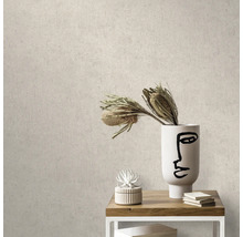Close-up van een beige betonlook behang in een interieur met tafel, decoratie en vaas.
