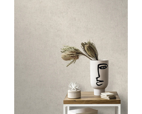 Close-up van een beige betonlook behang in een interieur met tafel, decoratie en vaas.